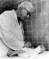 Virginia Apgar listening via stethescope to an infant's lung function